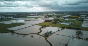 Aerial view of flooding in Angola with recovery efforts and green landscapes under a cloudy sky.